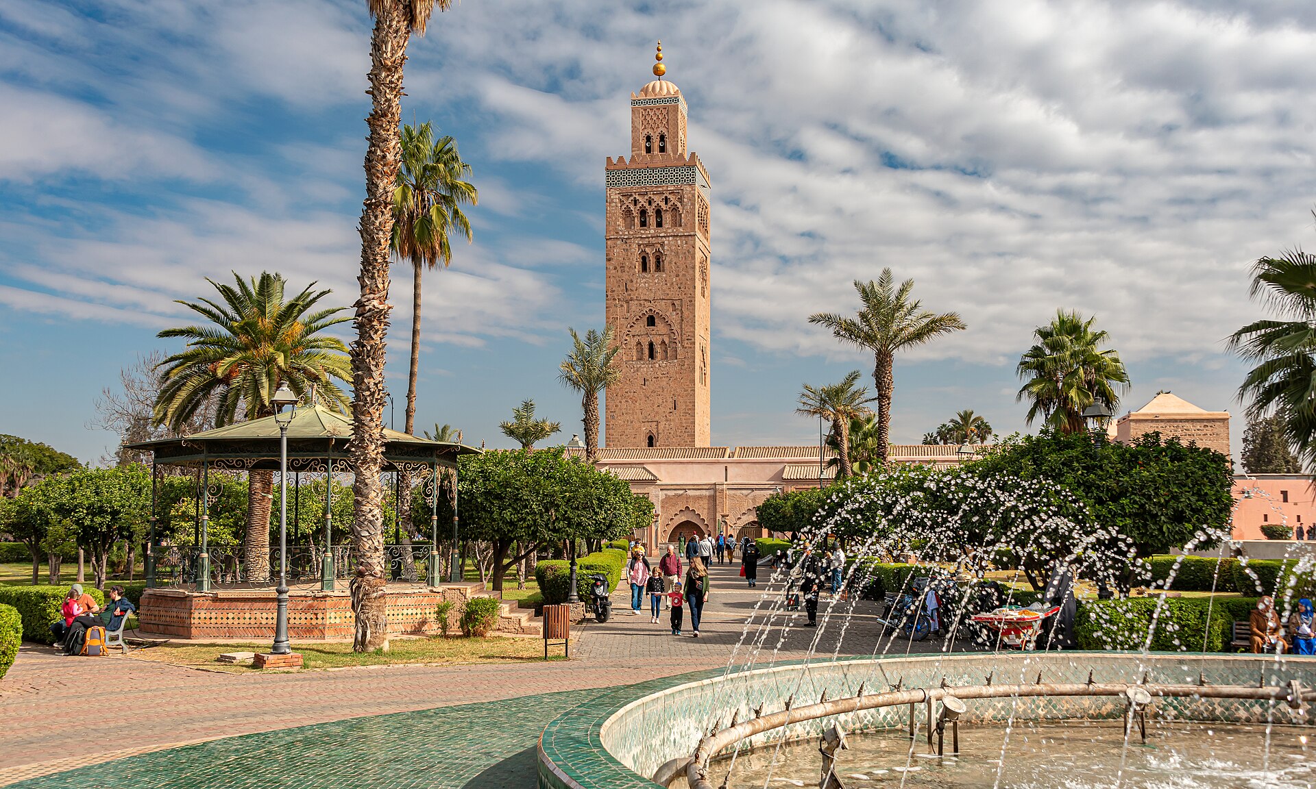 The Koutoubia Mosque minaret rising above a palm-lined garden and fountain in Marrakesh, Morocco