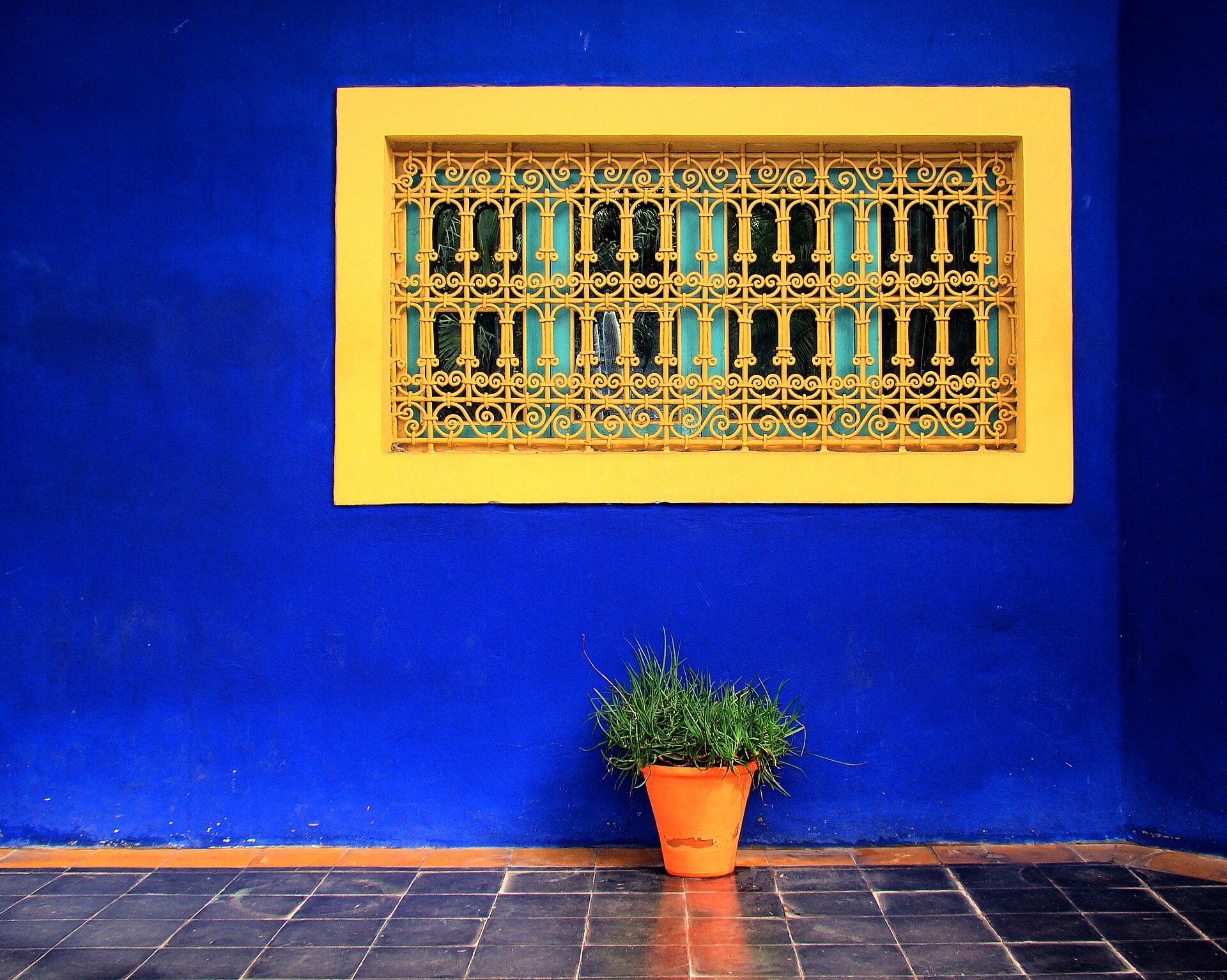 The iconic cobalt-blue wall and yellow window grille of Majorelle Garden in Marrakesh, Morocco