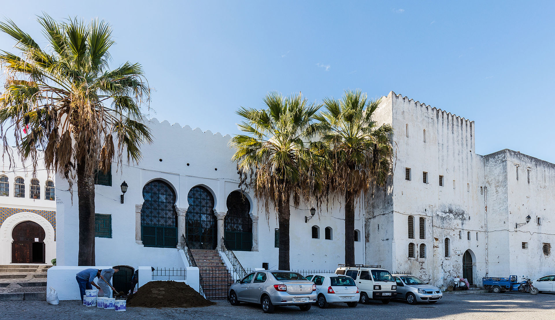The white kasbah building with arched Moorish windows and tall palm trees in Tangier's old medina, Morocco